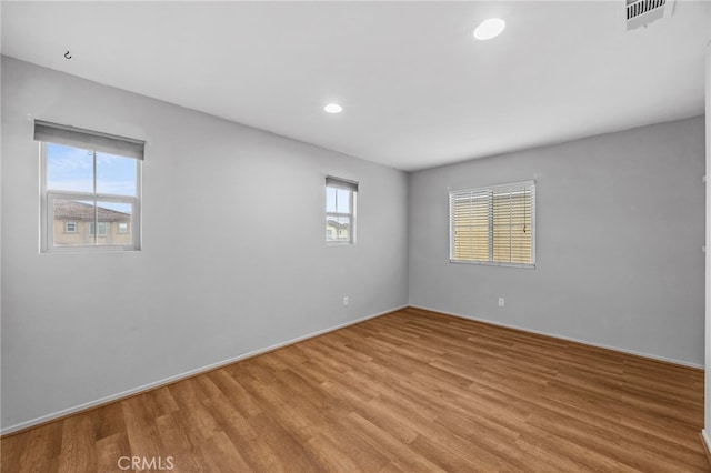 unfurnished room with a wealth of natural light, visible vents, recessed lighting, and light wood-type flooring