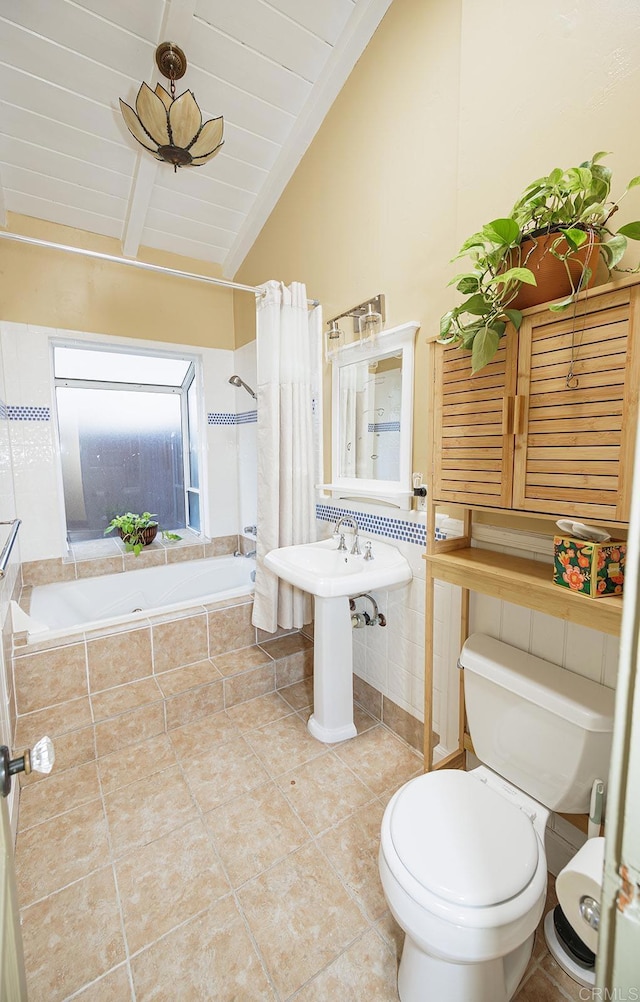 full bathroom with tile patterned flooring, toilet, lofted ceiling with beams, tiled shower / bath combo, and tile walls