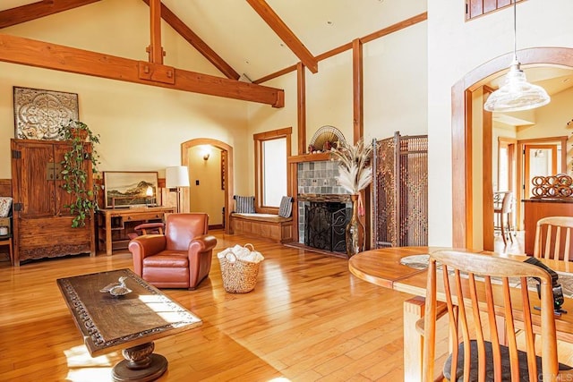 living room featuring arched walkways, high vaulted ceiling, beam ceiling, and hardwood / wood-style floors