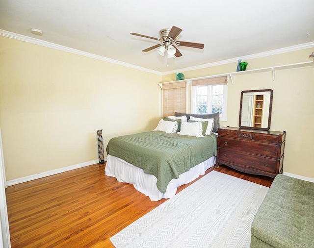 bedroom with a ceiling fan, crown molding, baseboards, and wood finished floors