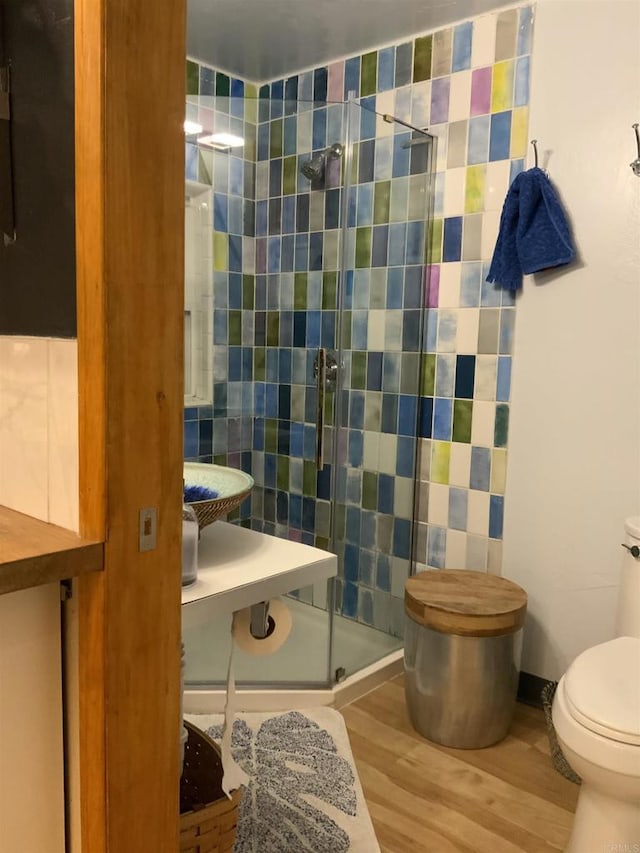 full bathroom with wood finished floors, toilet, and a stall shower