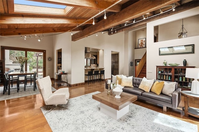 living area with baseboards, wood ceiling, wood finished floors, stairs, and rail lighting