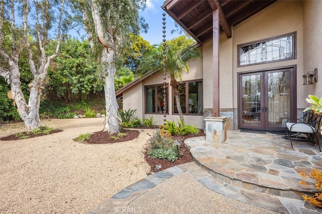 entrance to property featuring french doors, a patio area, and stucco siding