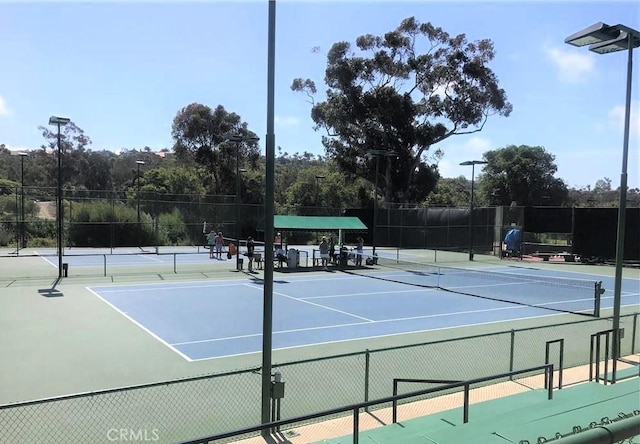 view of tennis court with community basketball court and fence