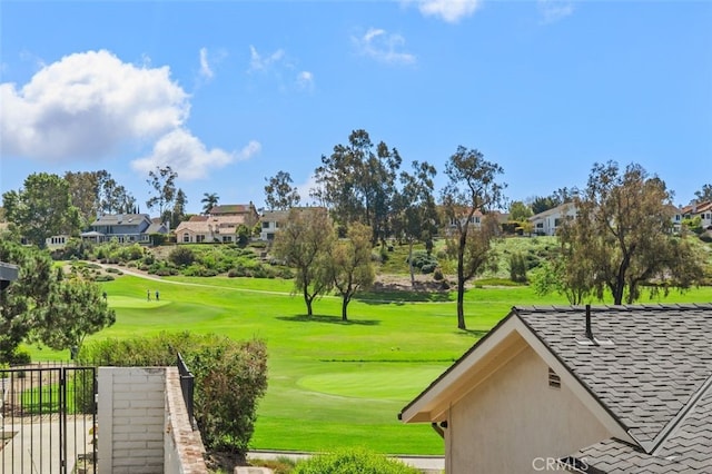 view of community with view of golf course, fence, and a lawn