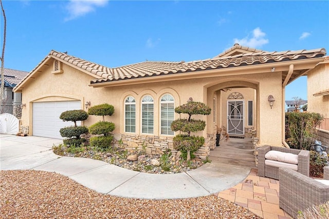 mediterranean / spanish-style house with a tile roof, concrete driveway, stucco siding, a garage, and stone siding