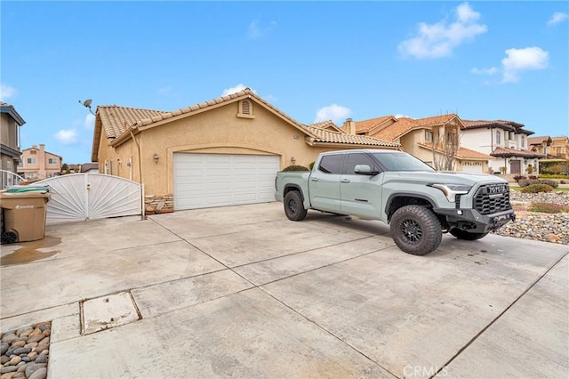 view of front of property with a tile roof, concrete driveway, a garage, and stucco siding