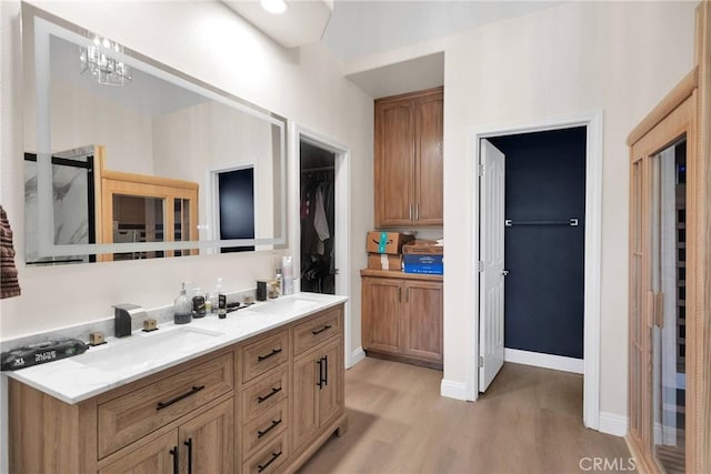 full bathroom with double vanity, wood finished floors, baseboards, and a sink