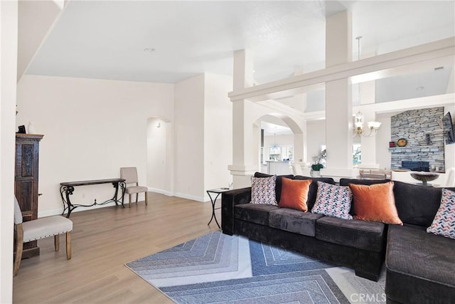 living room with baseboards, arched walkways, an inviting chandelier, and wood finished floors