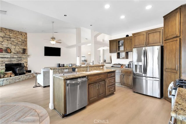 kitchen with open floor plan, light wood-style flooring, stainless steel appliances, a ceiling fan, and a sink