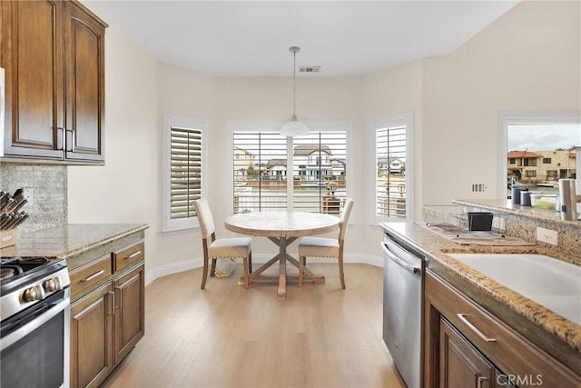 kitchen with visible vents, decorative backsplash, light wood-style flooring, hanging light fixtures, and stainless steel appliances