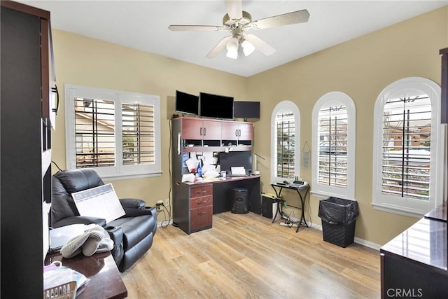 office space with light wood-style flooring, a ceiling fan, and baseboards