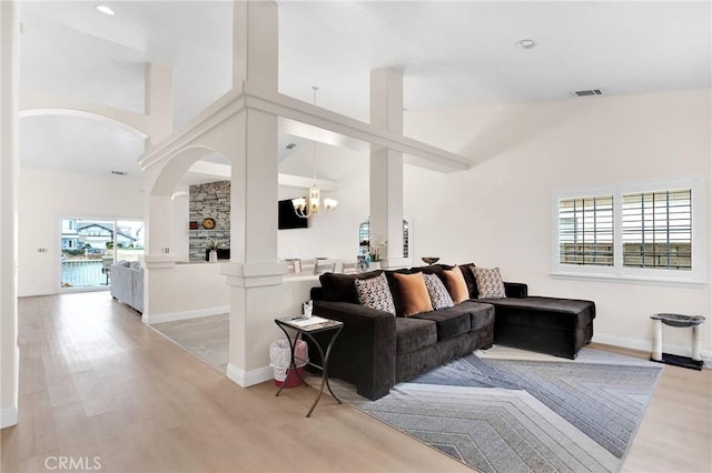 living room with arched walkways, visible vents, and light wood-type flooring