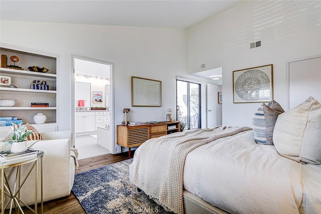 bedroom with ensuite bath, wood finished floors, visible vents, and high vaulted ceiling