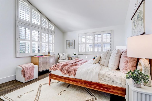 bedroom with baseboards, multiple windows, wood finished floors, and vaulted ceiling