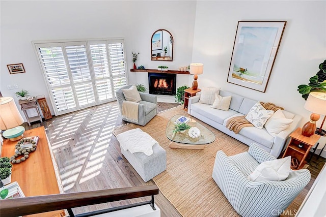 living area with a warm lit fireplace and wood finished floors