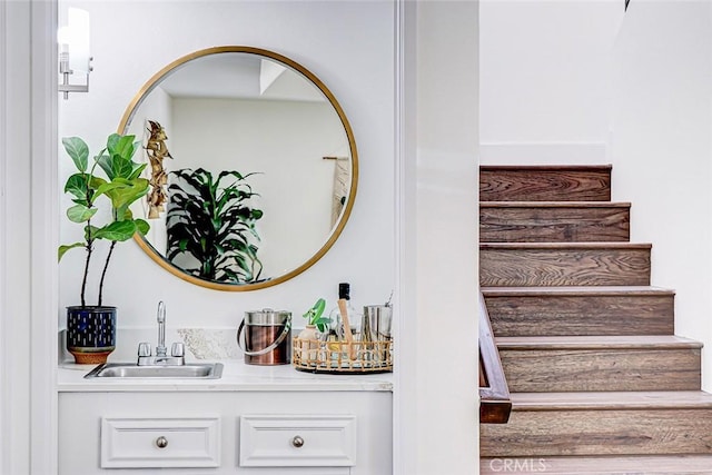 interior space featuring indoor wet bar, stairs, and a sink