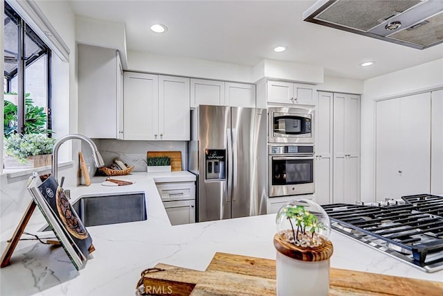 kitchen with light stone counters, recessed lighting, exhaust hood, stainless steel appliances, and a sink