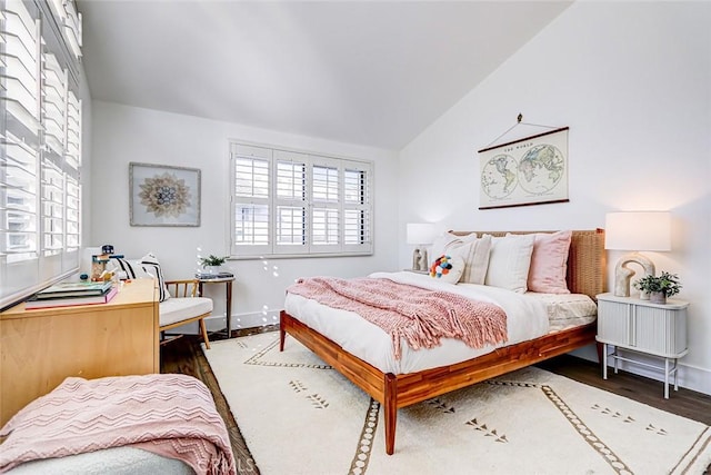 bedroom with multiple windows, wood finished floors, baseboards, and vaulted ceiling