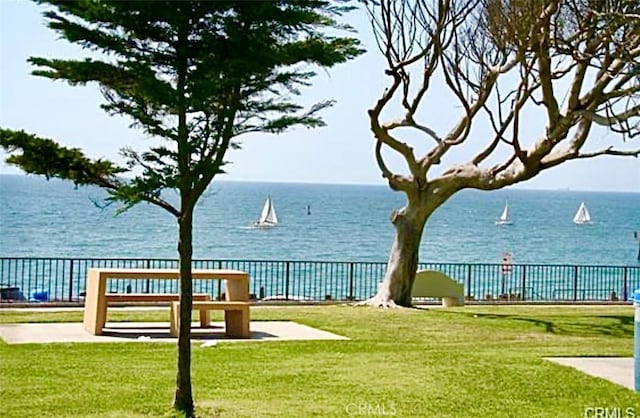 view of home's community with a water view, a lawn, and fence