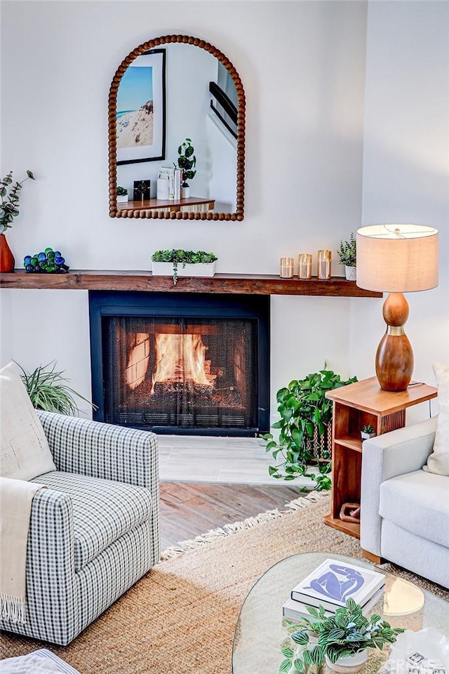 interior space with a warm lit fireplace and wood finished floors