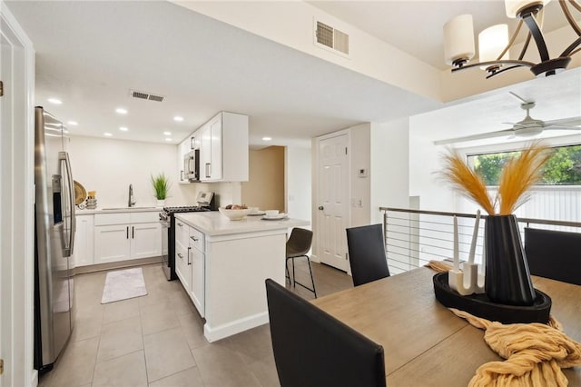 380 W Wilson St Unit A102, Costa Mesa, CA 92627 - kitchen with appliances with stainless steel finishes, light tile patterned floors, white cabinets, a kitchen breakfast bar, and recessed lighting