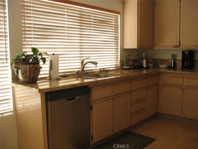 kitchen featuring dishwasher, light stone countertops, light wood-type flooring, and a sink