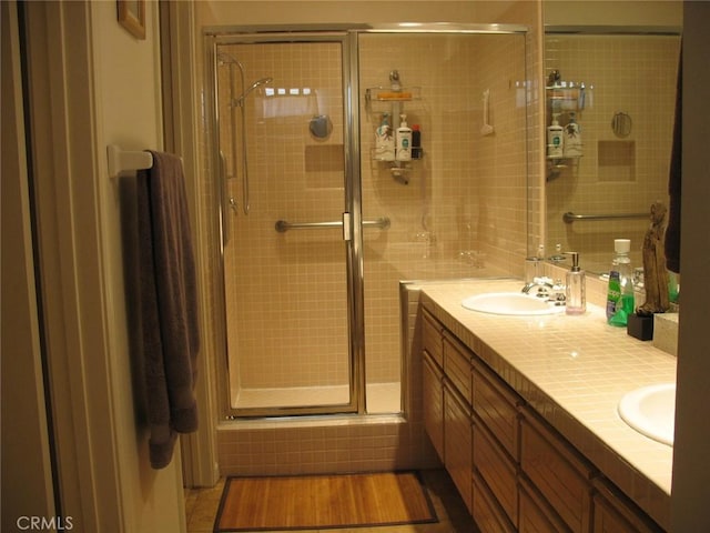 bathroom featuring double vanity, a shower stall, and a sink