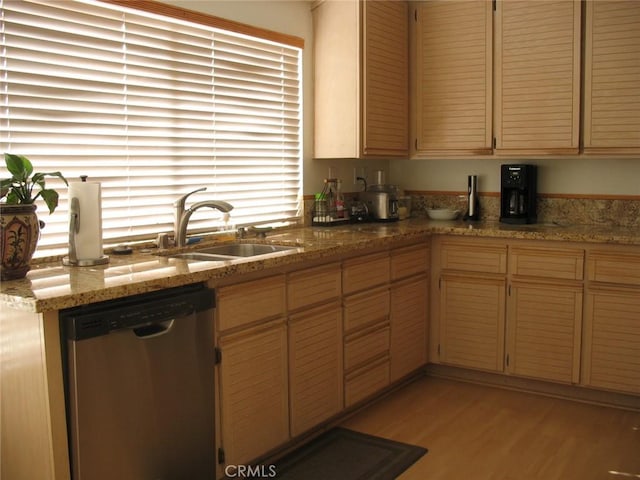 kitchen with a sink, light stone counters, dishwasher, and light wood finished floors