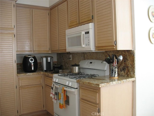 kitchen featuring decorative backsplash, white appliances, and light stone countertops