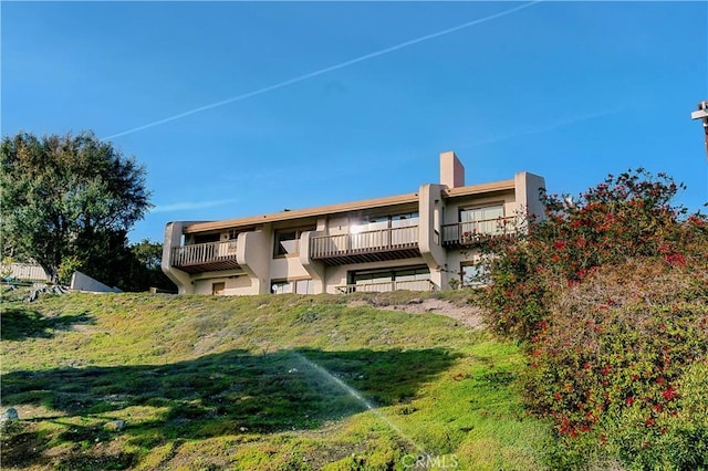 rear view of property with a balcony and stucco siding