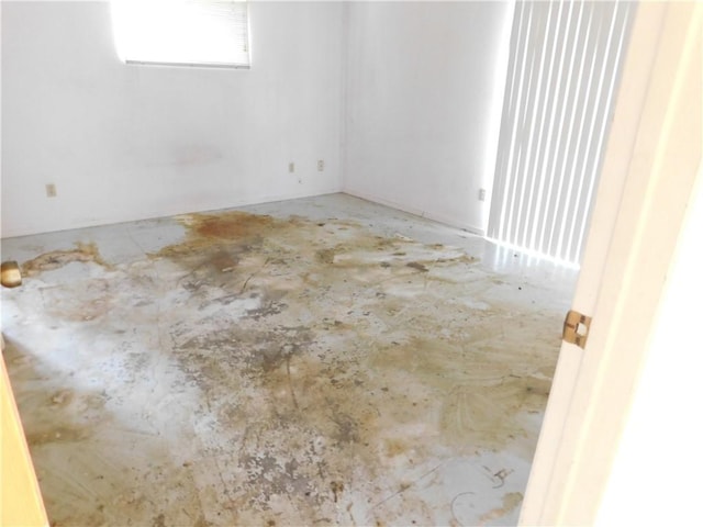 unfurnished room with unfinished concrete flooring