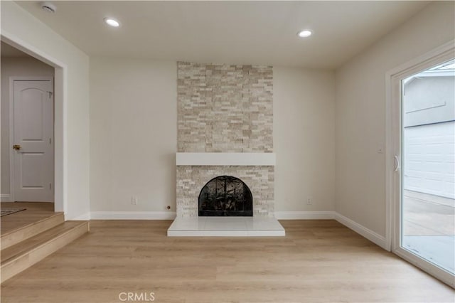 unfurnished living room featuring a stone fireplace, recessed lighting, baseboards, and light wood-style floors