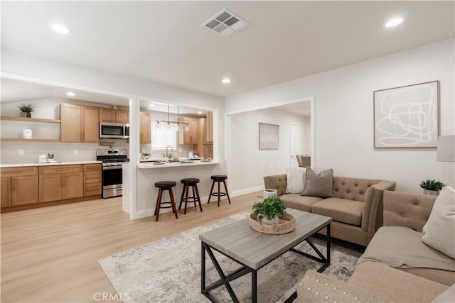 living room with recessed lighting, visible vents, light wood-style flooring, and baseboards