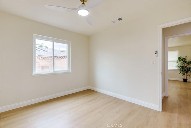 empty room with visible vents, light wood-style flooring, baseboards, and ceiling fan