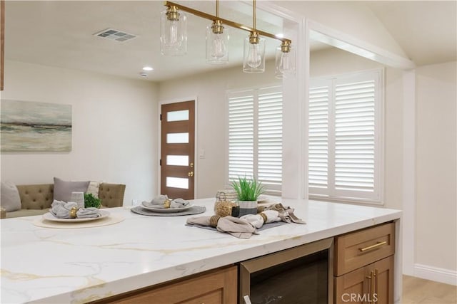 interior space with decorative light fixtures, visible vents, wine cooler, and light stone counters