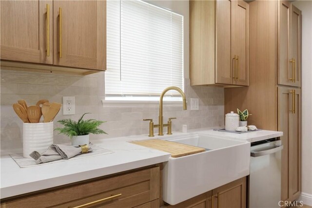 kitchen featuring decorative backsplash, stainless steel dishwasher, and light brown cabinetry