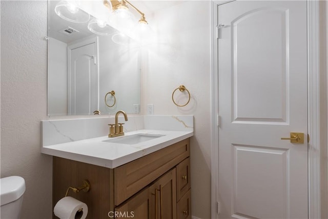 bathroom with visible vents, toilet, and vanity