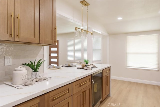 kitchen with light wood-style flooring, wine cooler, decorative backsplash, light stone countertops, and vaulted ceiling