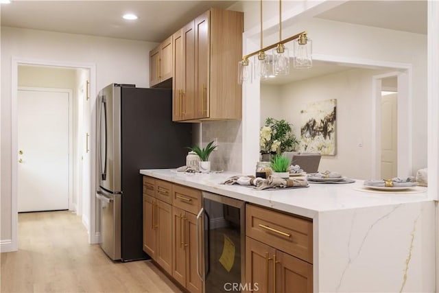 kitchen with tasteful backsplash, freestanding refrigerator, wine cooler, a peninsula, and light wood finished floors