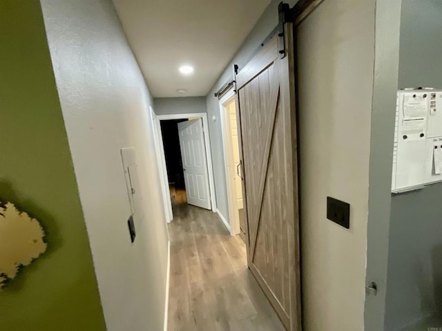 hallway featuring a barn door and light wood finished floors