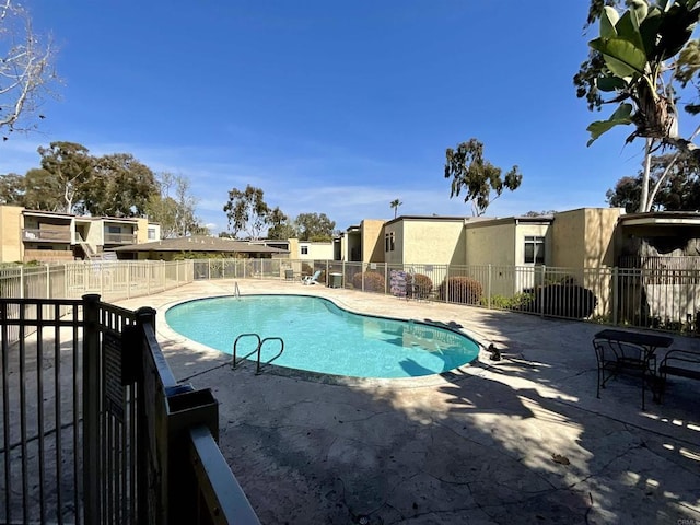 pool with a patio area, a residential view, and fence