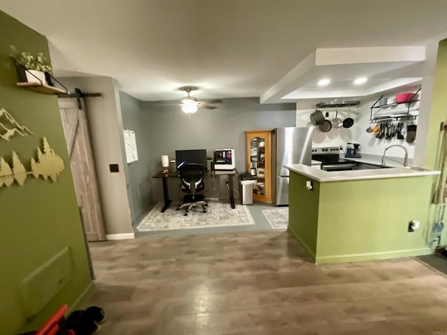 kitchen with a sink, stainless steel appliances, a barn door, green cabinets, and ceiling fan