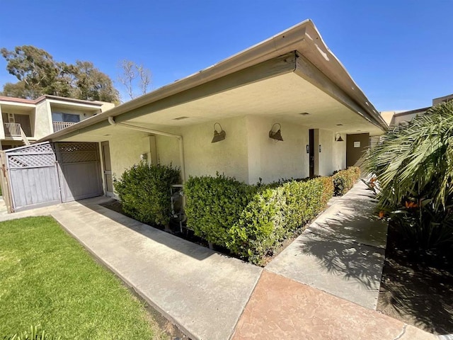 view of side of home featuring stucco siding and a gate