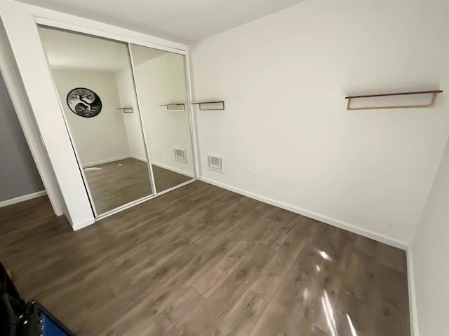 unfurnished bedroom with visible vents, baseboards, a closet, and wood finished floors