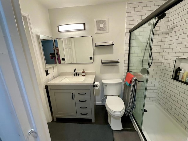 bathroom with a shower stall, vanity, and toilet