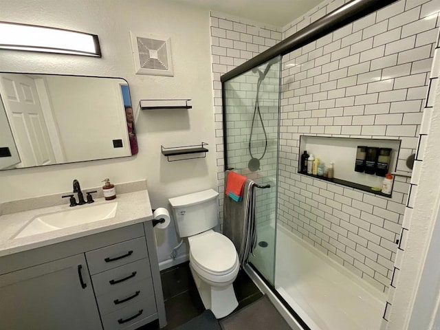 bathroom featuring vanity, toilet, visible vents, and tiled shower