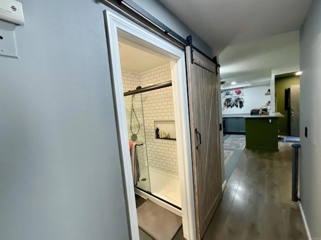 hall with a barn door and wood finished floors