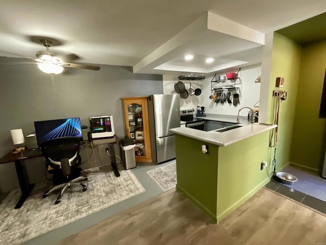 kitchen featuring light wood finished floors, appliances with stainless steel finishes, green cabinets, and a peninsula