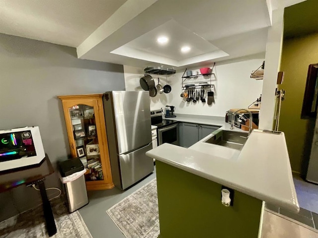 kitchen featuring a sink, finished concrete floors, stainless steel appliances, light countertops, and a raised ceiling